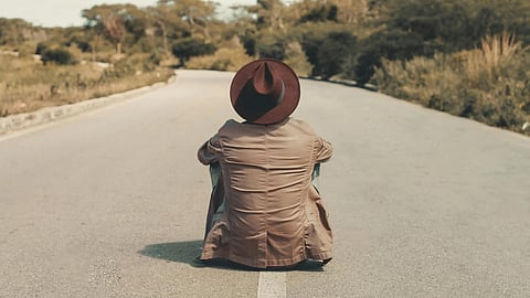 An image of a man sitting on road.