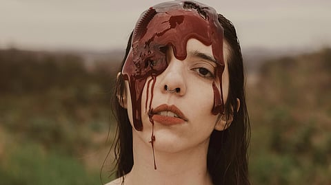 Image of a woman with blood dripping down her face, conveying a sense of distress and vulnerability.