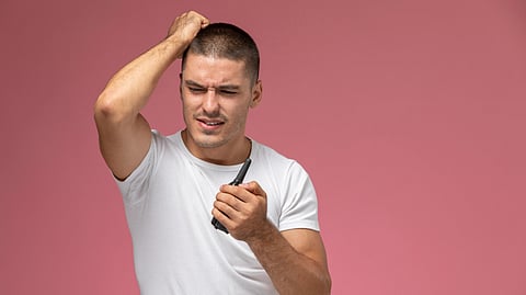 A man holds his head in frustration while staring at his phone screen.