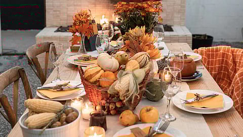 A beautifully arranged fall dinner table with candles, surrounded by autumn decor.