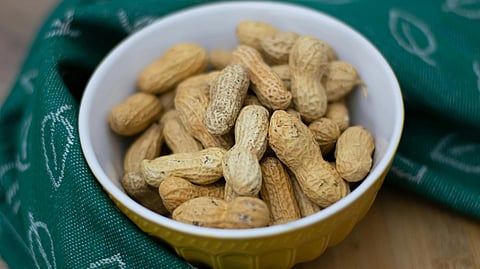 An image of peanuts in a bowl of yellow color surrounded with a green bowl.