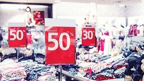 Clothing store interior with bright red discount signs showing "50%" and "30%".