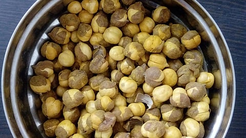 Image of roasted chana in a steel bowl on a table.