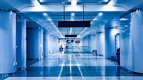 Spacious, blue-tinted airport hallway with shiny floors and ceiling lights. 