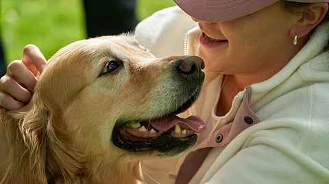 A woman gently pets a dog, smiling as they share a moment of affection together.