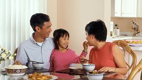 Image of a family sitting together at a table, smiling and enjoying their time during a meal.