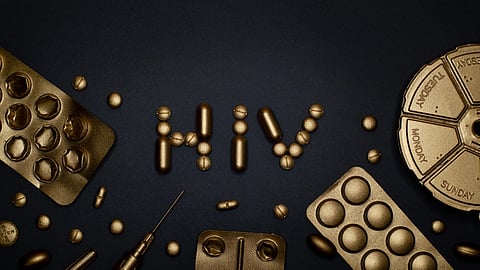 Image of golden capsules and tablets arranged to form the letters “HIV,” along with their outer coverings.