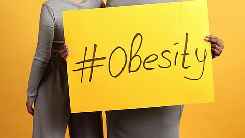 A yellow color poster having 'obesity' written over it.