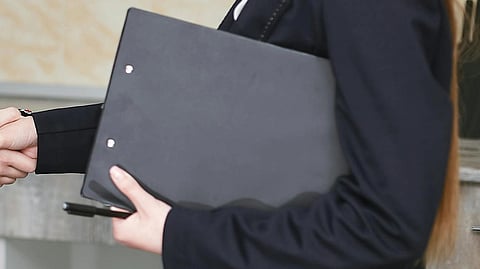 Image of a lawyer carrying a notepad while shaking hands with someone.