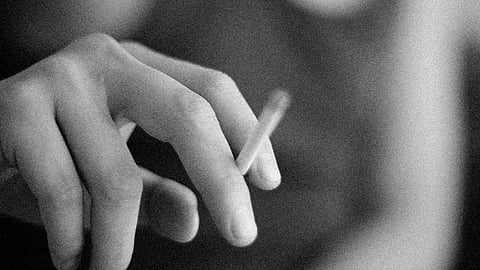 A person holding a cigarette between their fingers.