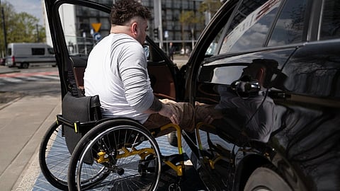 A man in wheelchair getting inside car.