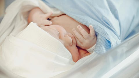 Image of a newborn baby wrapped in blue and white blankets.