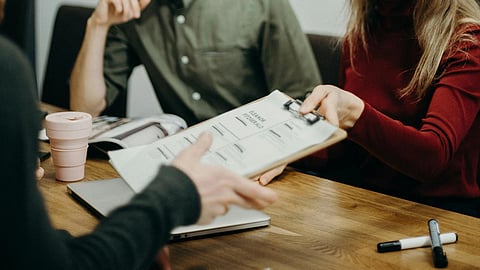 Image of a person conducting an interview, receiving a resume from a candidate.