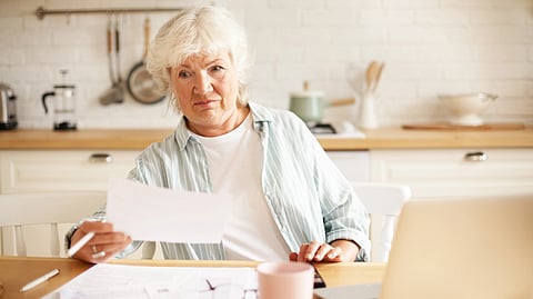 An image of a woman holding paper in her hand while wearing a blue shirt and a white t-shirt.