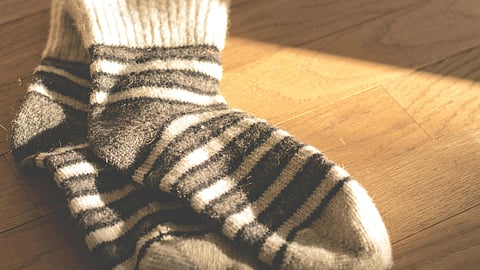 An image of a black-and-white striped pair of socks on a wooden floor.
