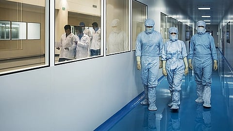 An image of scientists walking inside Biocon Park while wearing PPE kits.