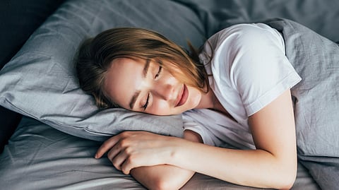 An image of a woman peacefully sleeping in bed with her eyes closed.