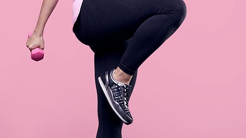 Close-up image of a woman doing cardio using a pink dumbbell.