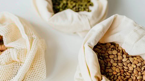 Image of different pulses in a cotton bag over a white surface.