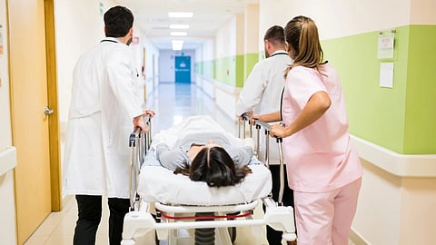 An image of medical staff pushing a stretcher with a patient down a hospital corridor. 