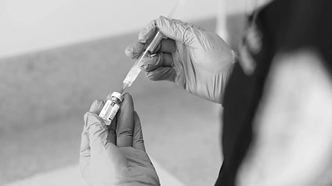 An image of a person wearing gloves holds a syringe, preparing for an HPV vaccination.
