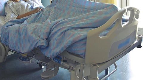Image of a patient resting in a hospital bed having blue sheets.