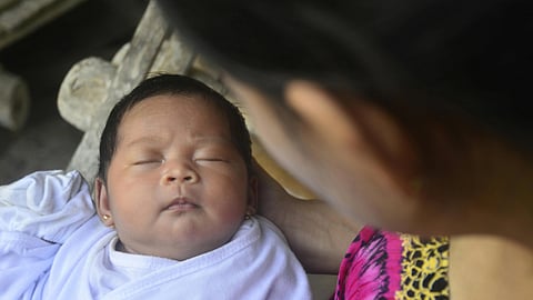 Image of a newborn baby peacefully sleeping, wrapped in a white cloth.