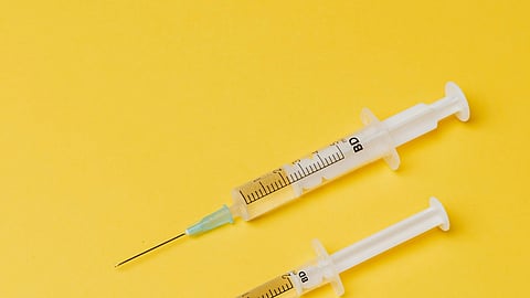 Image of 2 syringes in front of a yellow background.