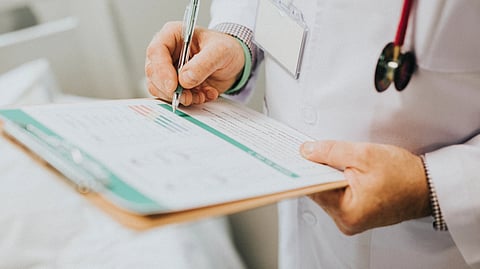 Image of a doctor writing a prescription on a writing pad.