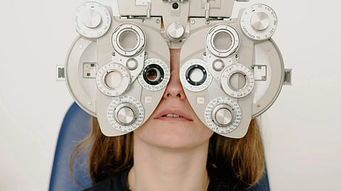 A woman wearing a black t-shirt getting her eyes checked using advanced equipment.