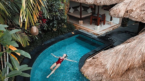 Image of a woman in red color swimming suit in a pool of a luxury rehab center.