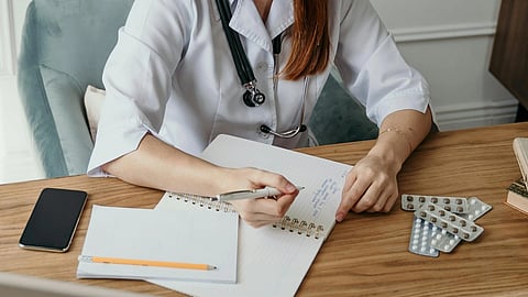 An image of a doctor on desk writing something.
