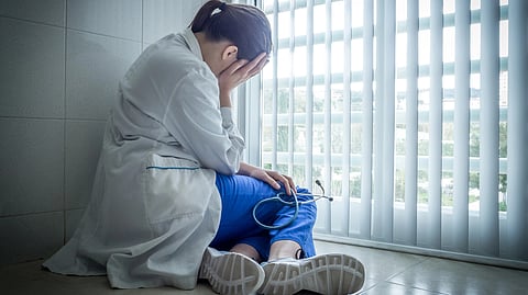 depressed female doctor sitting in despair near hospital window