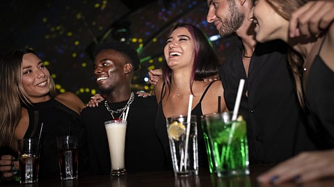A group of young people having drinks on the counter. 
