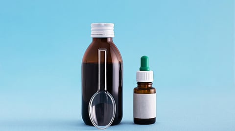 A brown glass bottle and plastic spoon nearby. 