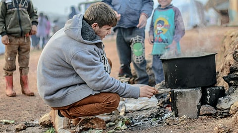 An image of refugees cooking in a pot on fire.