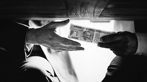 Hands passing money under the table indicating corruption and bribery.
