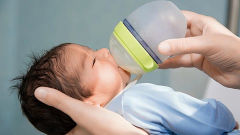 A newborn is being fed formula from a bottle.