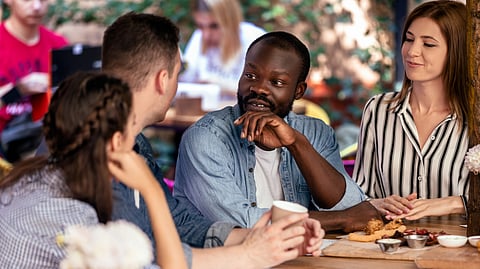 An image of a group of friends conversing at a cozy outdoor café table.