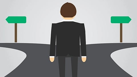 An image of a man in a suit stands at a fork in the road.