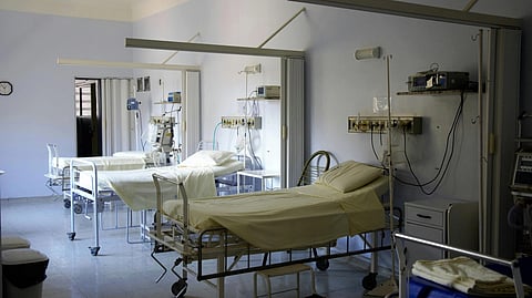 An image of empty hospital room with three beds, each with medical equipment and monitors attached. 