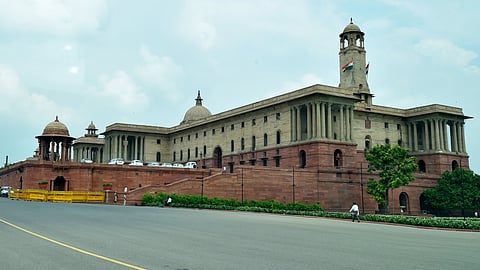 An image of majestic cream and red sandstone building with columns and domes under a cloudy sky
