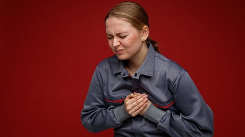 A woman suffering a heart attack clutching her chest in pain. 