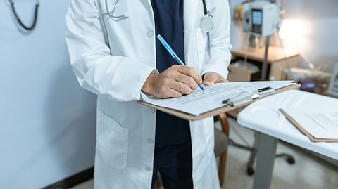 An image of a male doctor holding a writing pad.
