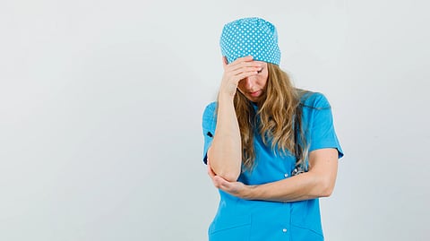 A tired nurse with her hands on her head. 