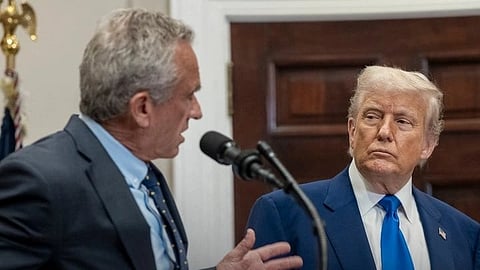 A man stands with Donald Trump and speaks into a microphone.