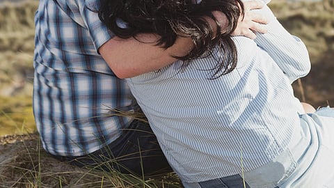 Image of a couple sitting on a mountain cliff.
