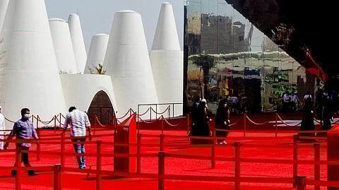 Image of an expo with red carpets and a few people walking around.