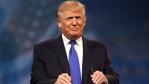 An image of Donald Trump stands at a podium, gesturing with his hands.