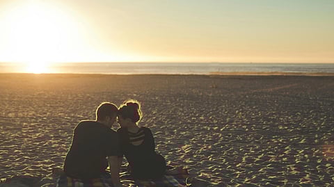 Image of a couple posing together in the desert against a sunset backdrop.